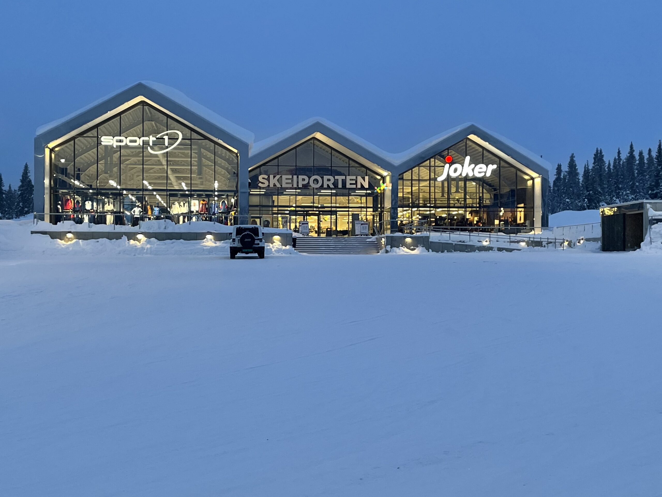 Skeiporten med butikker og opplyste vinduer i vinterkvelden.