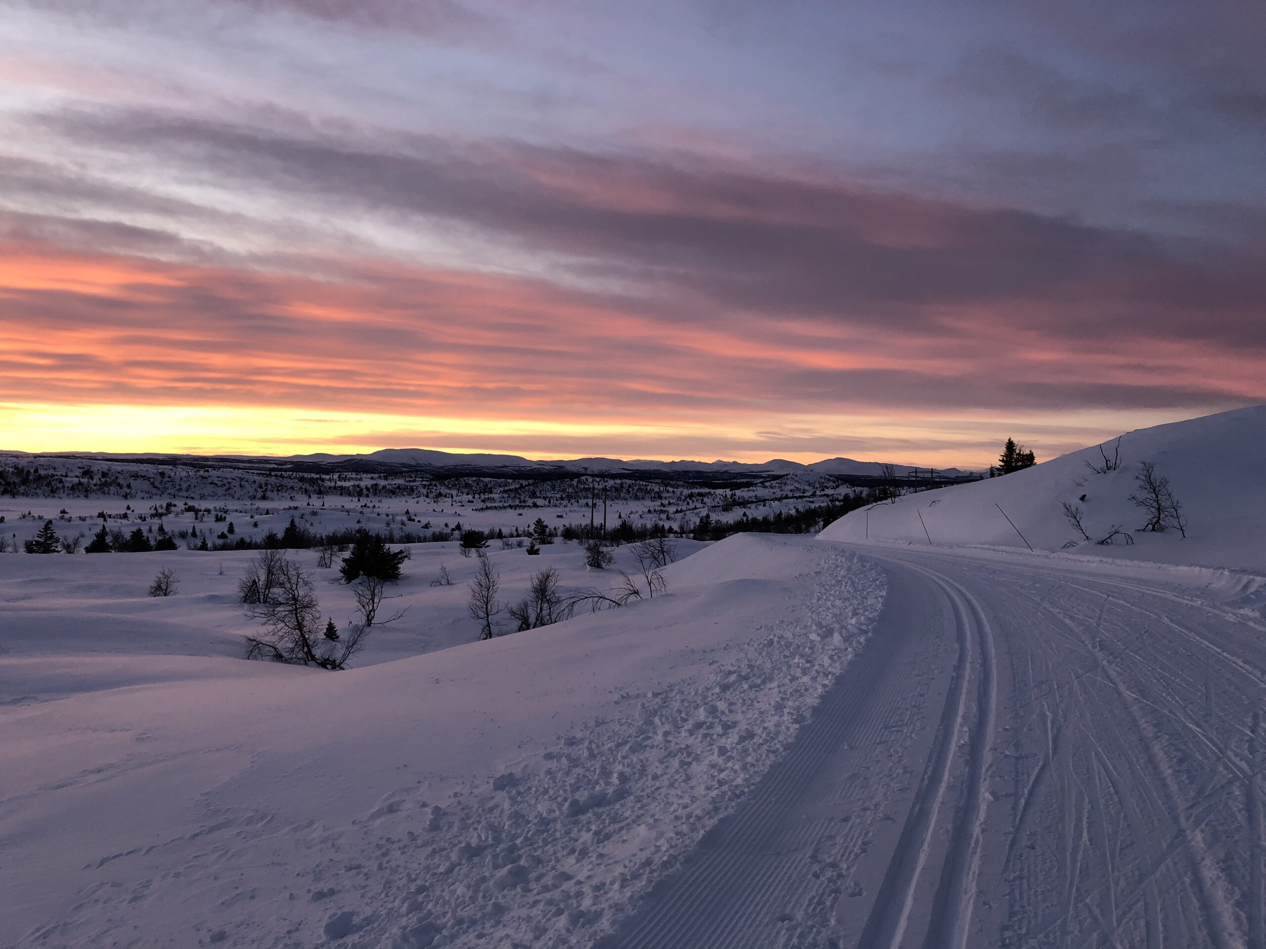 Preparert skiløype i fjellandskapet rundt Skeikampen under en fargerik kveldshimmel.